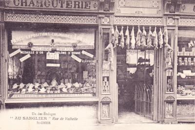 Ce commerce de charcuterie, chez M. G Dupont est bien achalandée. On peut y voir les poulets dans la vitrine et les lapins qui pendent au dessus de la porte. 